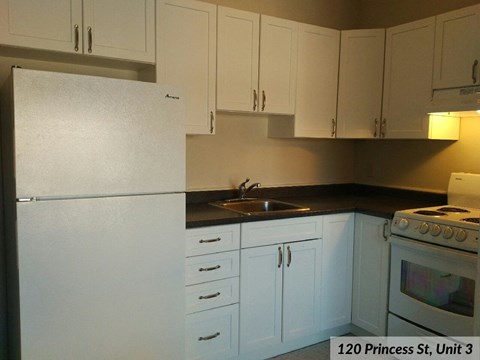 an empty kitchen with white cabinets and a white refrigerator